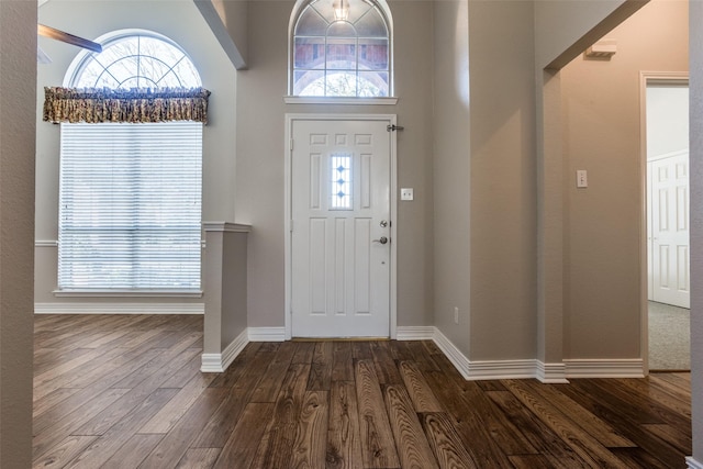 foyer entrance featuring a towering ceiling and dark hardwood / wood-style floors