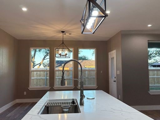 kitchen featuring light stone countertops, sink, decorative light fixtures, a chandelier, and plenty of natural light