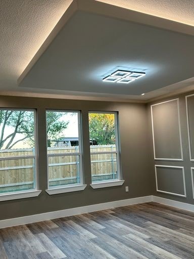 unfurnished room featuring a textured ceiling, hardwood / wood-style flooring, and ornamental molding