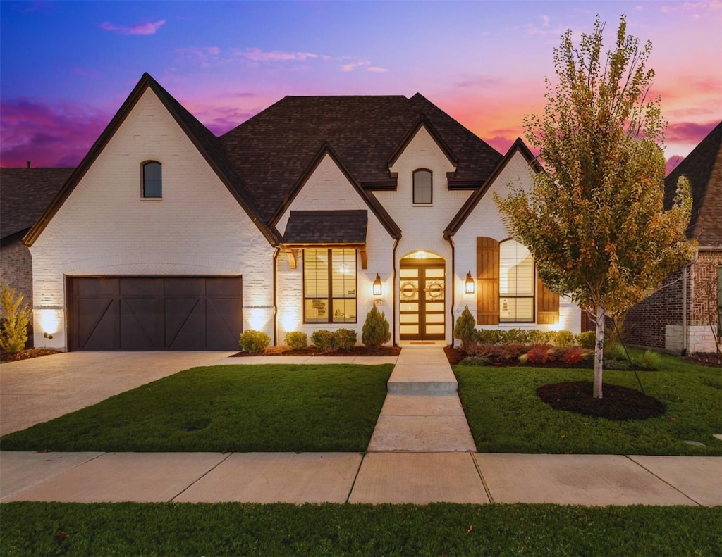 french country style house featuring a garage, a yard, and french doors