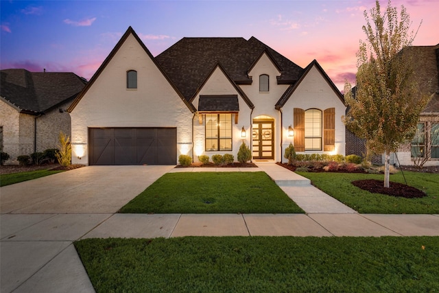 french country style house featuring a lawn, french doors, and a garage