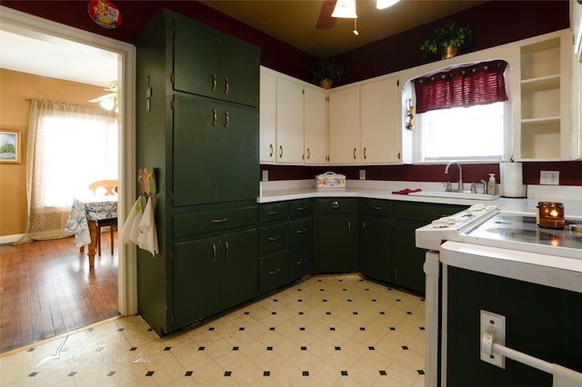 kitchen featuring white cabinets, stove, plenty of natural light, and sink