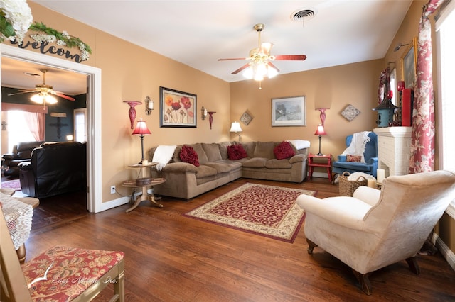 living room with dark hardwood / wood-style floors, ceiling fan, and a fireplace