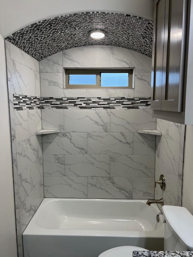 bathroom with toilet and tiled shower / bath