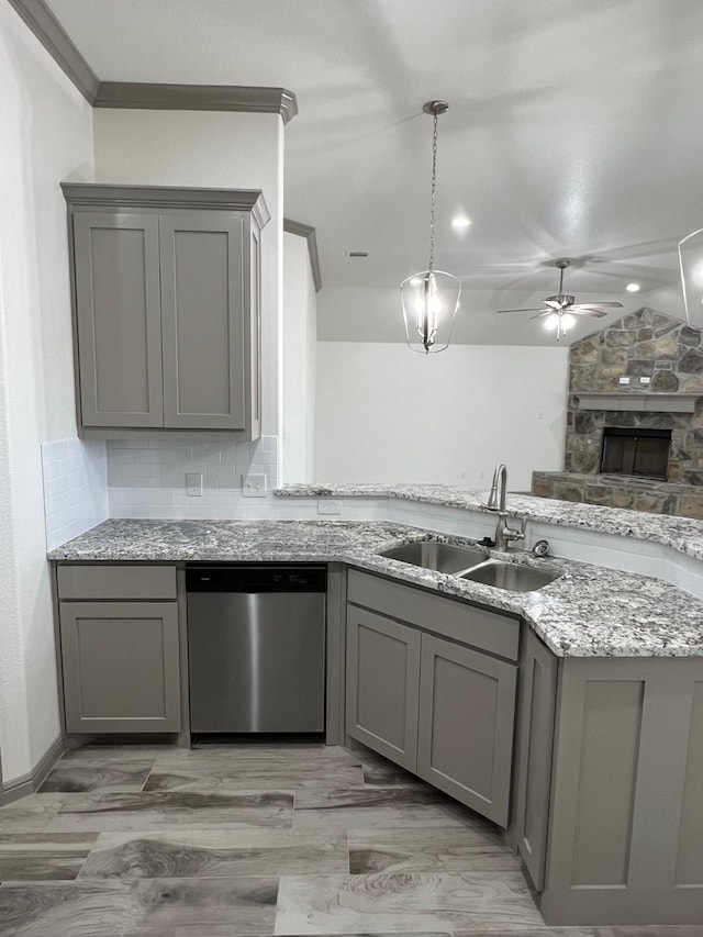 kitchen with ceiling fan, dishwasher, sink, a stone fireplace, and gray cabinets