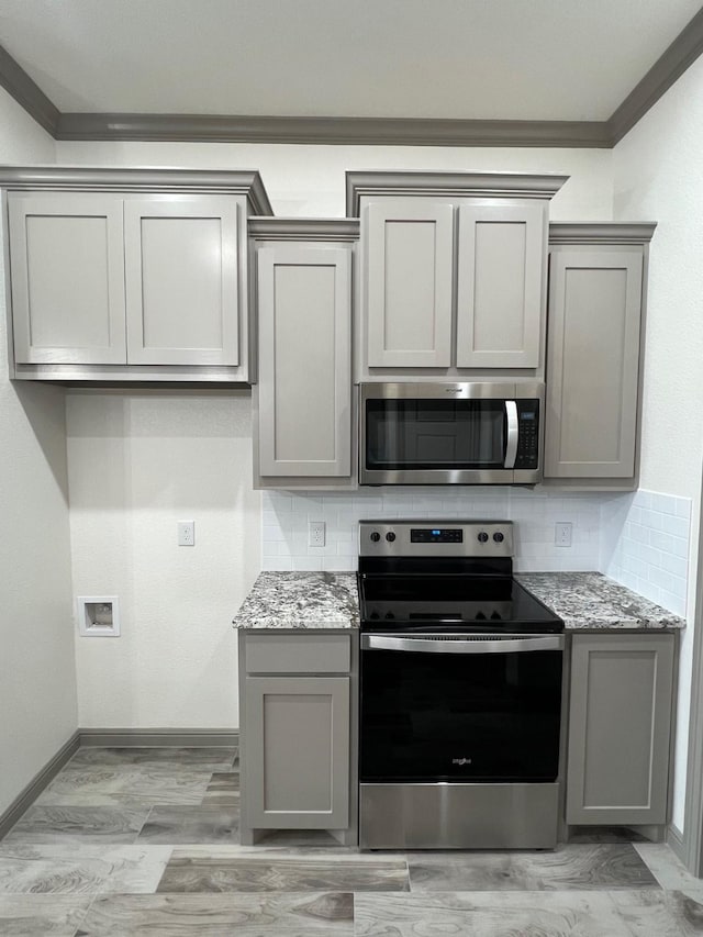 kitchen with light stone countertops, stainless steel appliances, and gray cabinetry