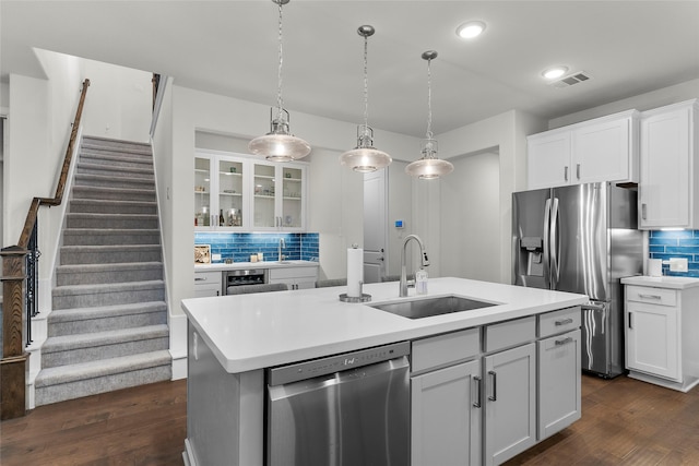 kitchen featuring white cabinetry, stainless steel appliances, decorative backsplash, sink, and a kitchen island with sink