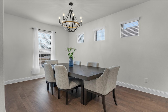 dining area with dark wood-type flooring and an inviting chandelier