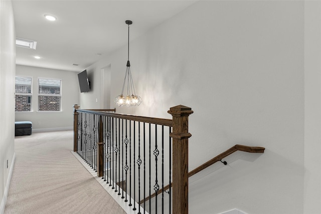 hall featuring light carpet and an inviting chandelier