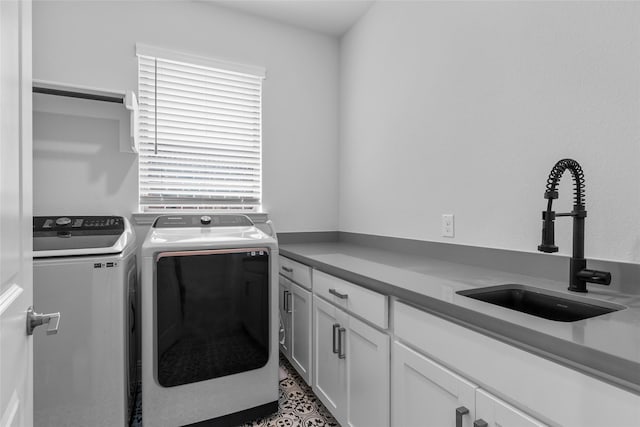 clothes washing area featuring sink, separate washer and dryer, and cabinets