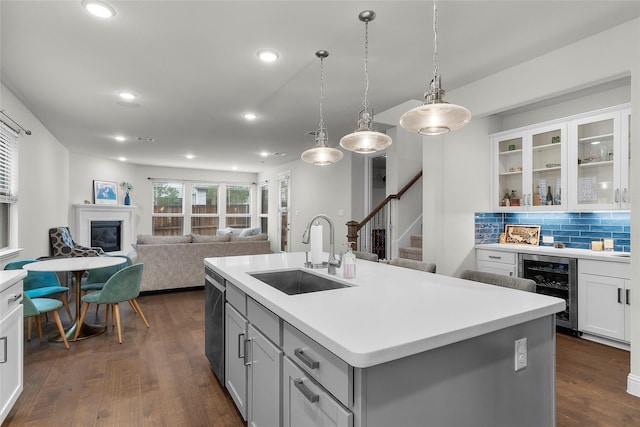 kitchen featuring backsplash, a center island with sink, sink, white cabinetry, and beverage cooler