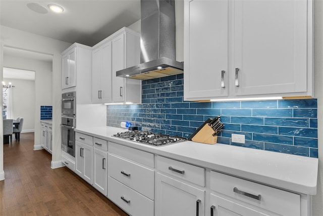 kitchen featuring white cabinetry, decorative backsplash, dark wood-type flooring, stainless steel gas cooktop, and wall chimney range hood