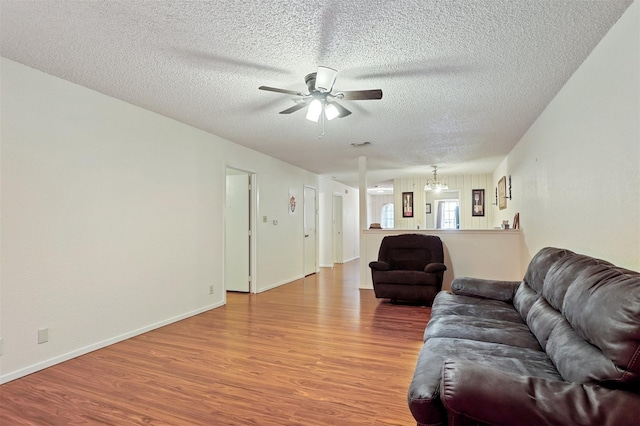 living room featuring a textured ceiling, ceiling fan with notable chandelier, and hardwood / wood-style flooring