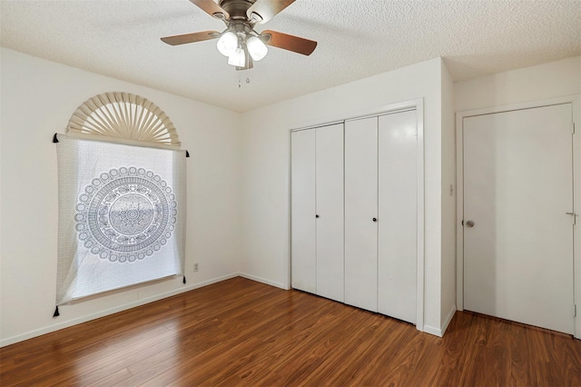 unfurnished bedroom with ceiling fan, dark hardwood / wood-style flooring, and a textured ceiling