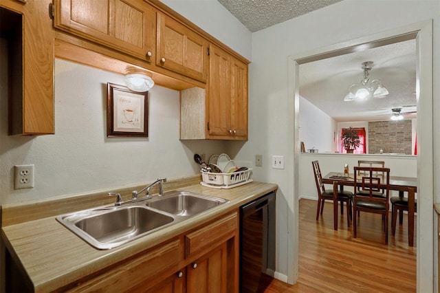 kitchen with sink, hanging light fixtures, wine cooler, light hardwood / wood-style flooring, and a textured ceiling