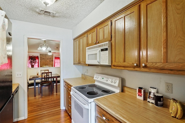 kitchen featuring a textured ceiling, white appliances, light hardwood / wood-style flooring, a notable chandelier, and hanging light fixtures