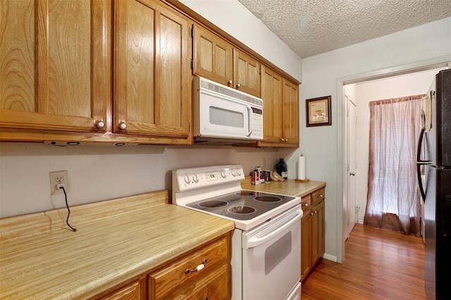 kitchen featuring wood-type flooring, white appliances, and a textured ceiling