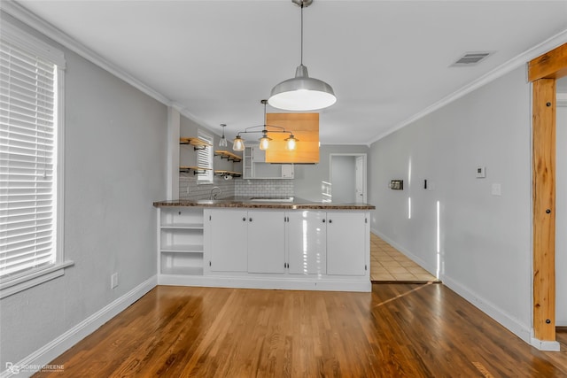 kitchen with sink, crown molding, hanging light fixtures, kitchen peninsula, and white cabinets