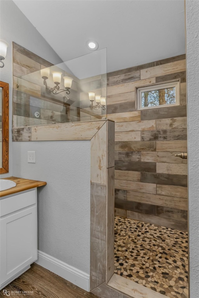 bathroom with hardwood / wood-style floors, vanity, and a tile shower