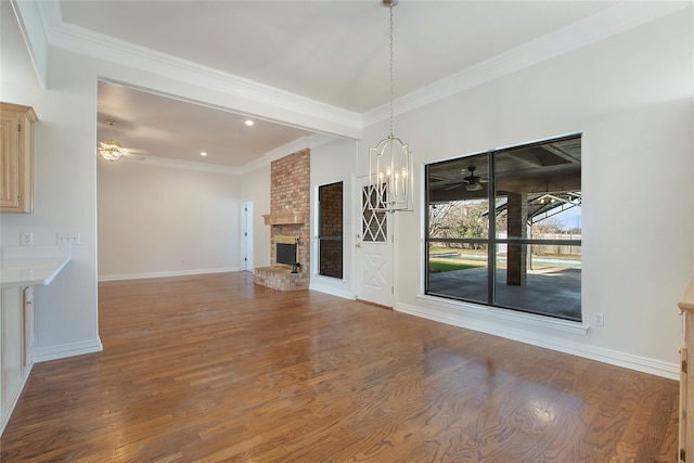 unfurnished living room with a fireplace, wood-type flooring, an inviting chandelier, and ornamental molding