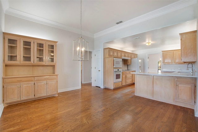 kitchen with light brown cabinetry, crown molding, kitchen peninsula, white appliances, and light hardwood / wood-style floors