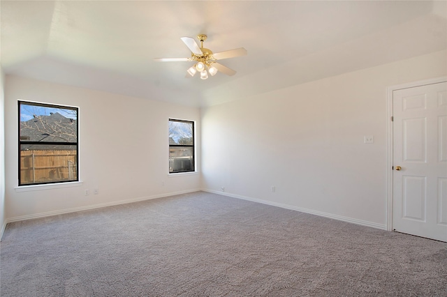 empty room with a tray ceiling, ceiling fan, and carpet