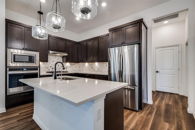 kitchen with dark wood-type flooring, dark brown cabinetry, stainless steel appliances, and an island with sink