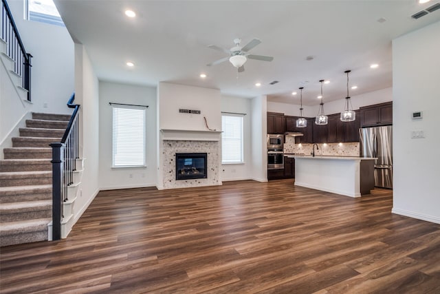 unfurnished living room featuring ceiling fan, dark wood-type flooring, and sink