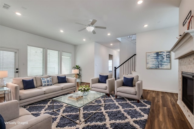 living room with ceiling fan, dark hardwood / wood-style floors, and a tiled fireplace