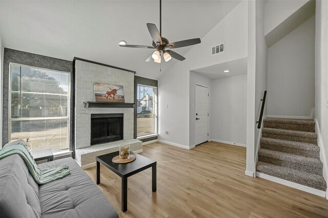 living room featuring ceiling fan, light hardwood / wood-style floors, lofted ceiling, and a fireplace