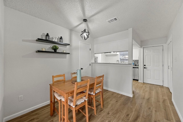 dining area featuring light wood-type flooring and a textured ceiling