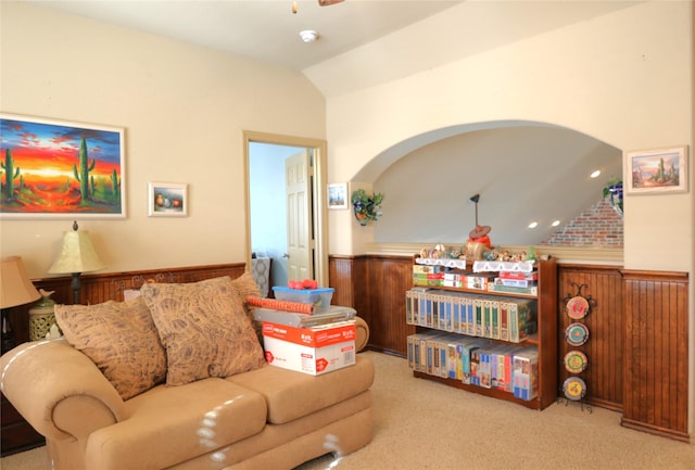 living room featuring lofted ceiling, light colored carpet, and wooden walls