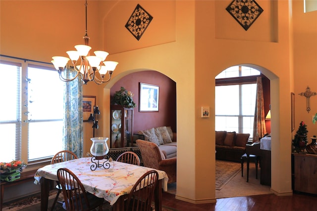 dining room featuring a towering ceiling, hardwood / wood-style floors, and an inviting chandelier