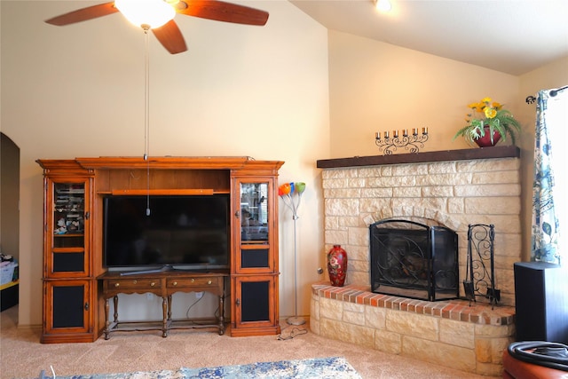 carpeted living room featuring lofted ceiling, a stone fireplace, and ceiling fan