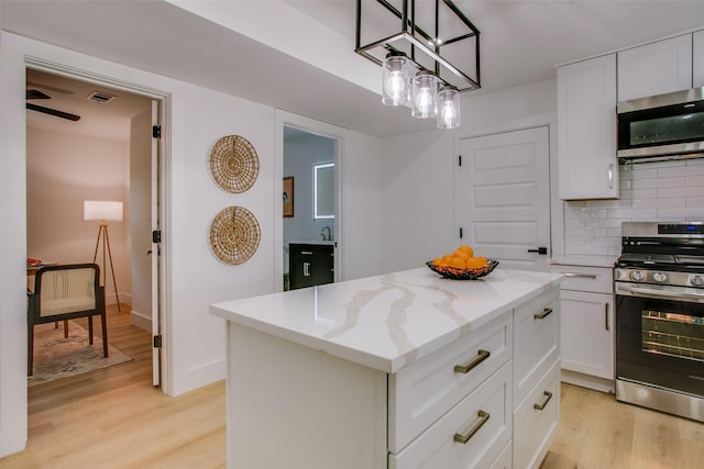 kitchen featuring backsplash, white cabinets, appliances with stainless steel finishes, decorative light fixtures, and a kitchen island