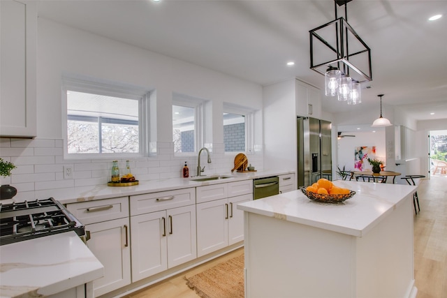 kitchen with white cabinetry, a center island, decorative light fixtures, and appliances with stainless steel finishes