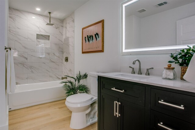 full bathroom with hardwood / wood-style floors, vanity, toilet, and tiled shower / bath