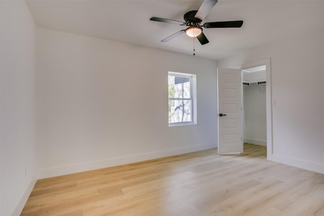 unfurnished bedroom featuring a closet, light hardwood / wood-style floors, a spacious closet, and ceiling fan