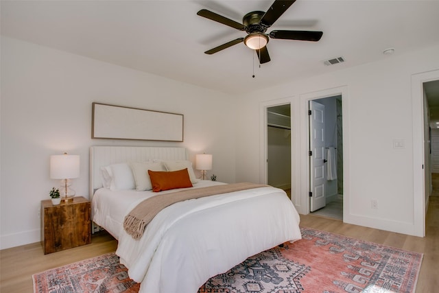 bedroom with a walk in closet, ceiling fan, connected bathroom, light hardwood / wood-style floors, and a closet