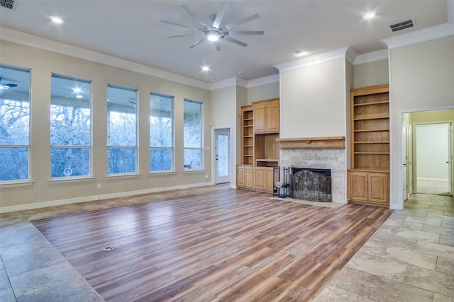 unfurnished living room featuring built in shelves, ceiling fan, light hardwood / wood-style flooring, crown molding, and a fireplace