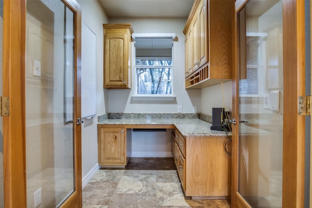 kitchen featuring light stone counters and built in desk