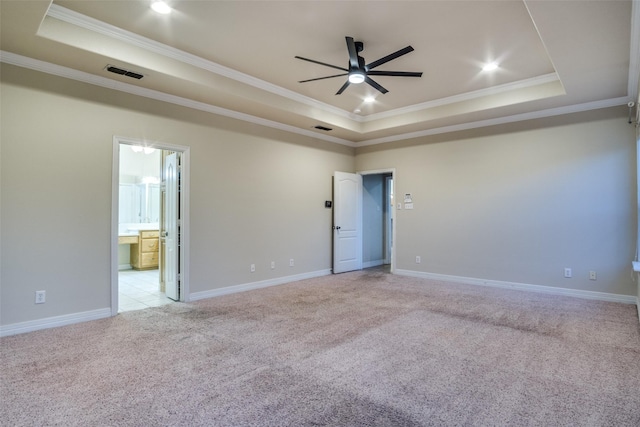 empty room featuring a tray ceiling, light carpet, crown molding, and ceiling fan