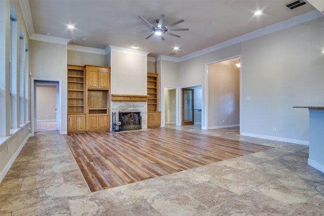 unfurnished living room featuring a stone fireplace, ceiling fan, and crown molding