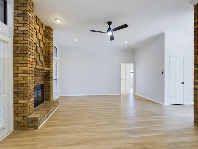 unfurnished living room featuring ceiling fan, ornamental molding, light hardwood / wood-style floors, and a brick fireplace