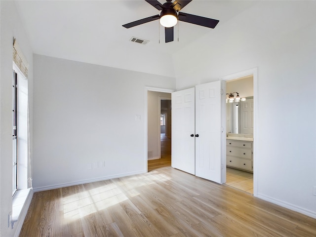 unfurnished bedroom with ceiling fan, ensuite bathroom, vaulted ceiling, and light hardwood / wood-style flooring