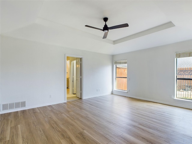 spare room with ceiling fan, a raised ceiling, and light hardwood / wood-style flooring