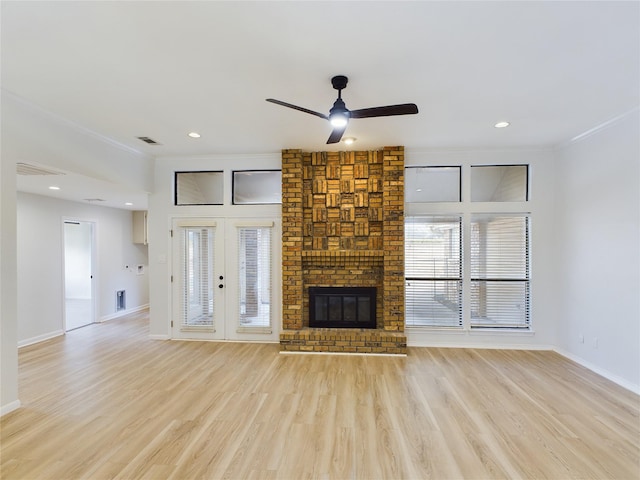 unfurnished living room featuring light hardwood / wood-style flooring, a fireplace, ornamental molding, and french doors