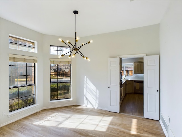 unfurnished dining area featuring a chandelier and light wood-type flooring