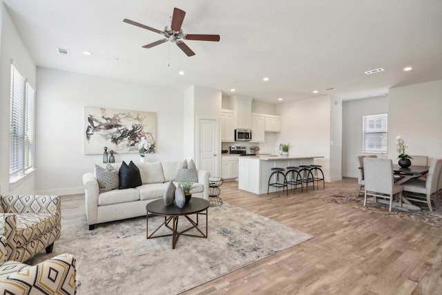 living room featuring ceiling fan, a healthy amount of sunlight, and light wood-type flooring