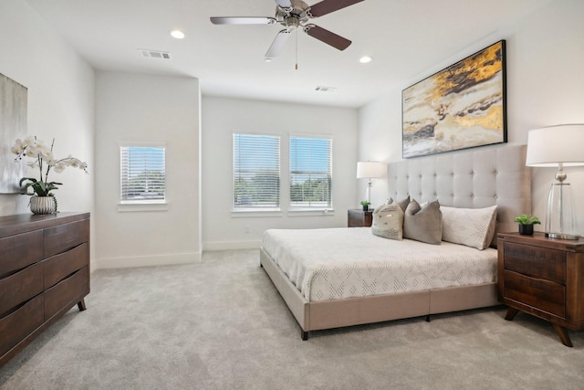 bedroom featuring ceiling fan, light colored carpet, and multiple windows